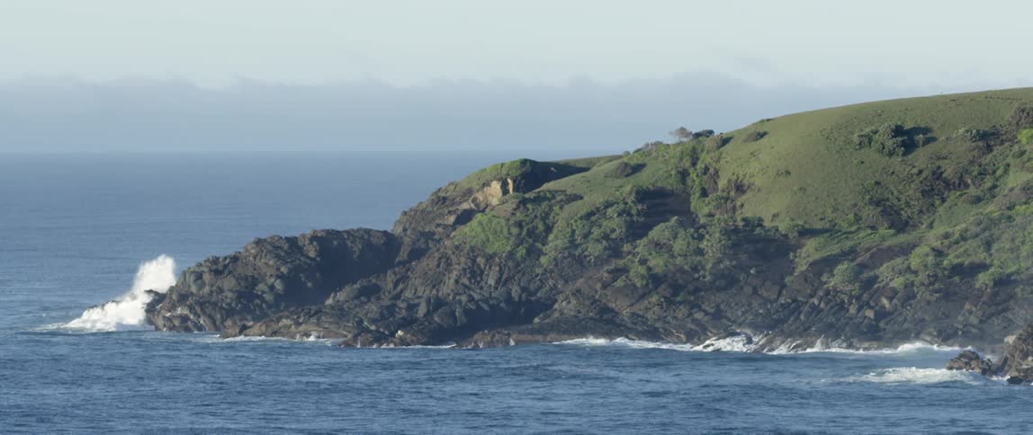 Ocean waves crash against a rocky promontory