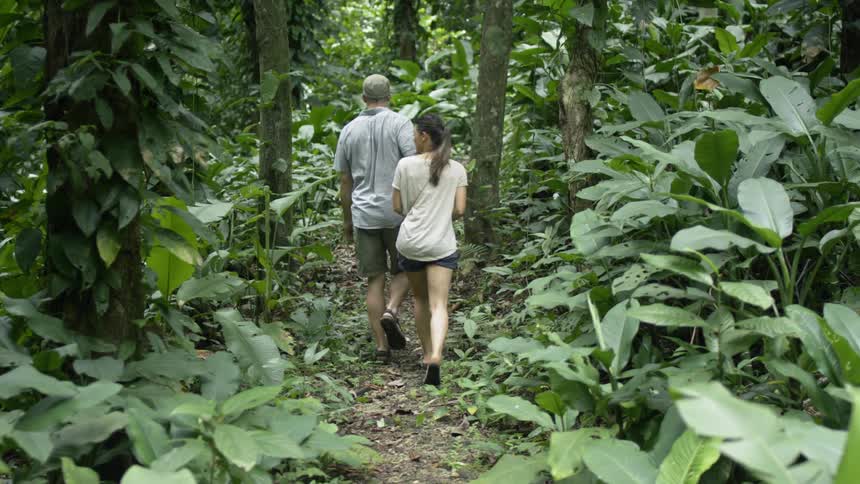 A man and woman hike through the forest