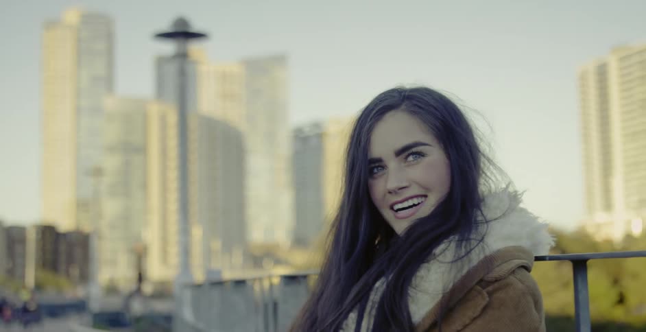 Woman looks around and smiles in a city on a sunny day