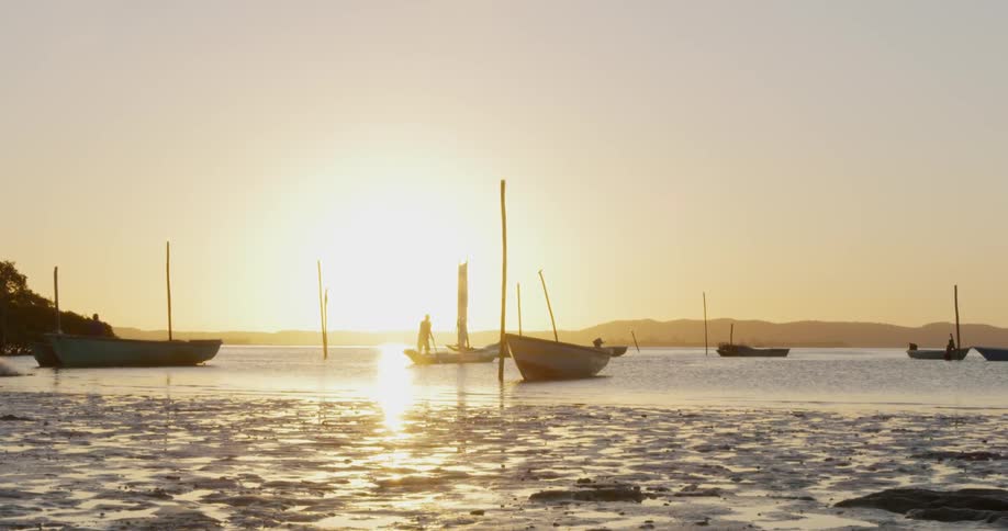 Boats float on a lake of water as the sun sets