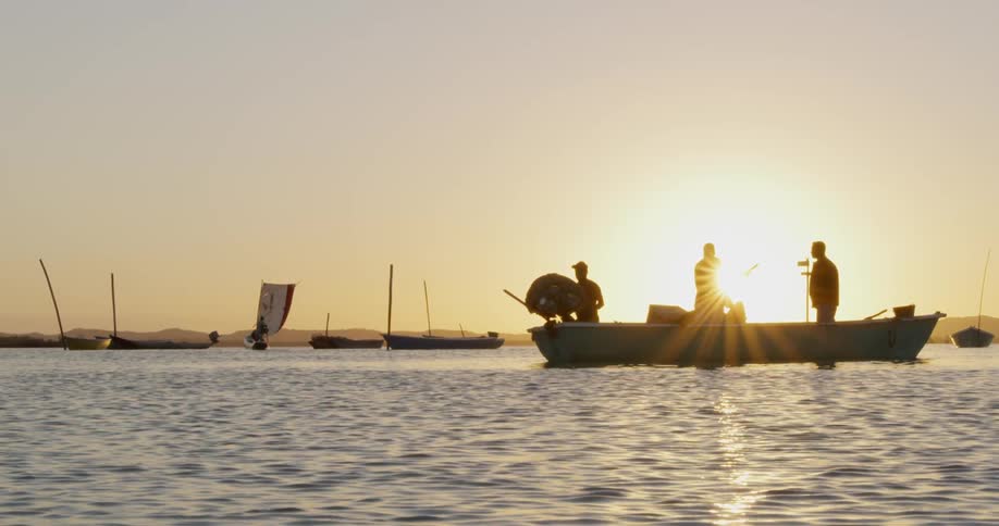 People fish off a fishing boat at sunset