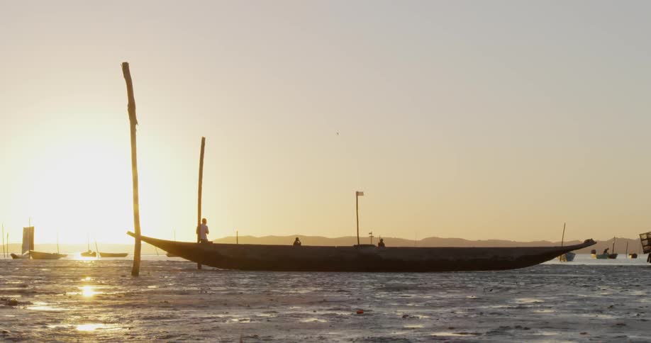 Boat parked on a sandy beach at sunset
