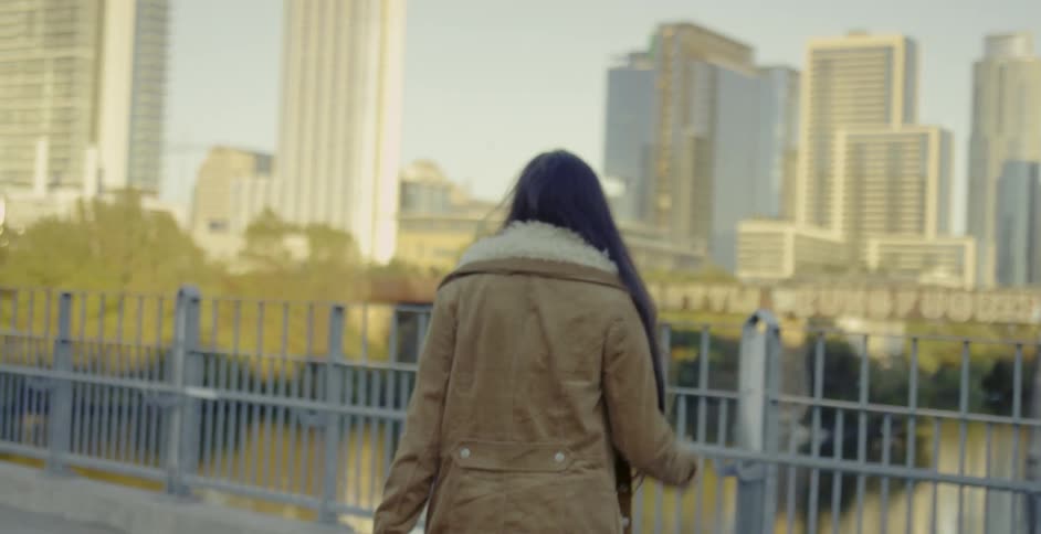 A woman walks over to water to look at the buildings