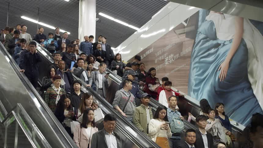 People are riding an escalator down in an asian city