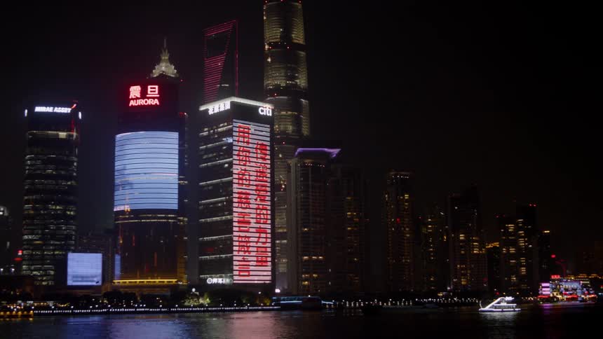 Buildings in an asian city display signs and images at night