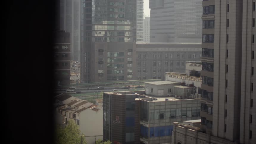 Vehicles are traveling on a highway in the middle of a city in daylight