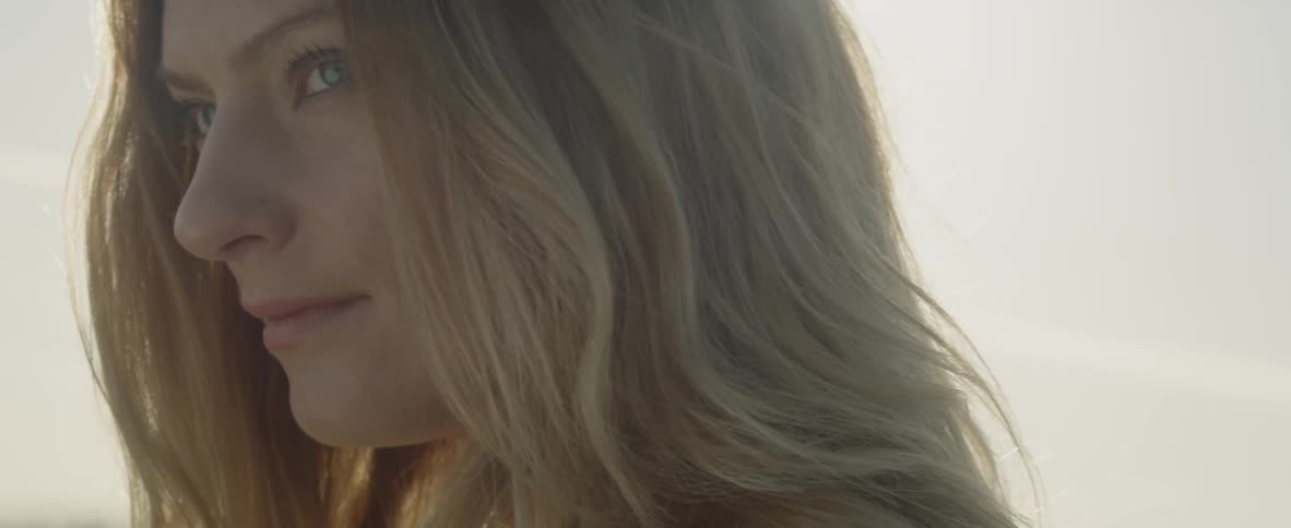 A woman looks around smiling outside