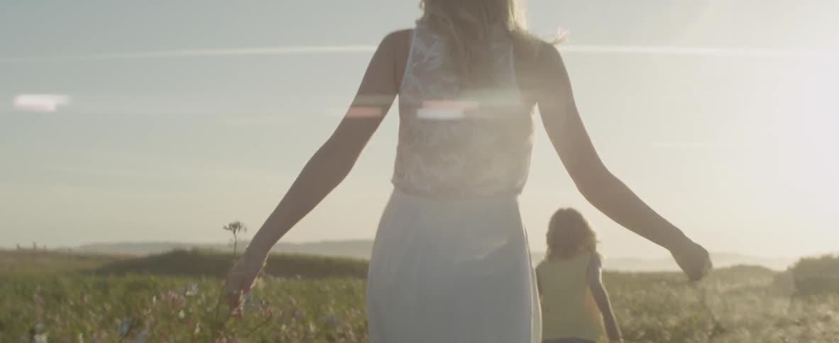 A woman and child walk through the flowers on the field