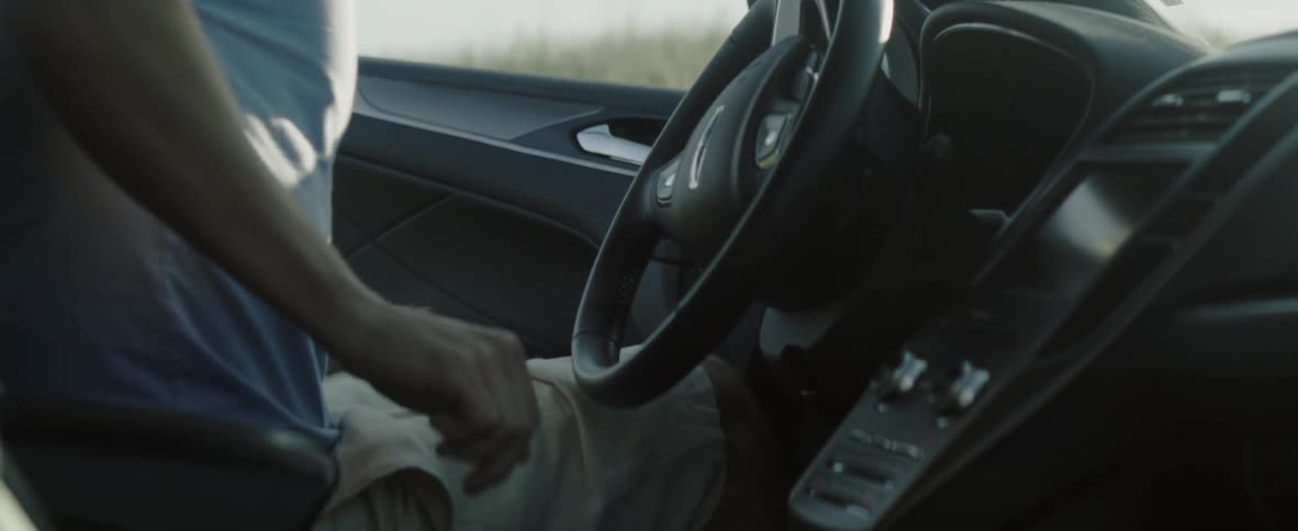 A man gets into a car and sits in the driver's seat