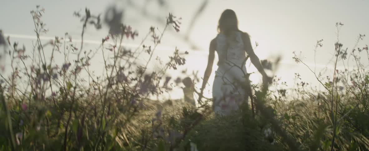 A woman and children run through a grass field