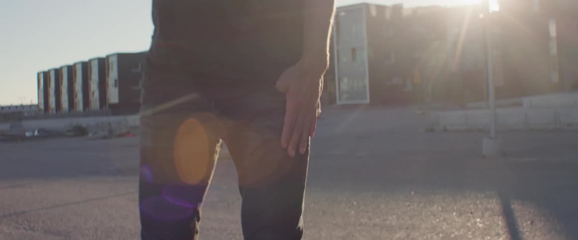 Golden evening sunlight creates a bright lens flare as a man walks outside.