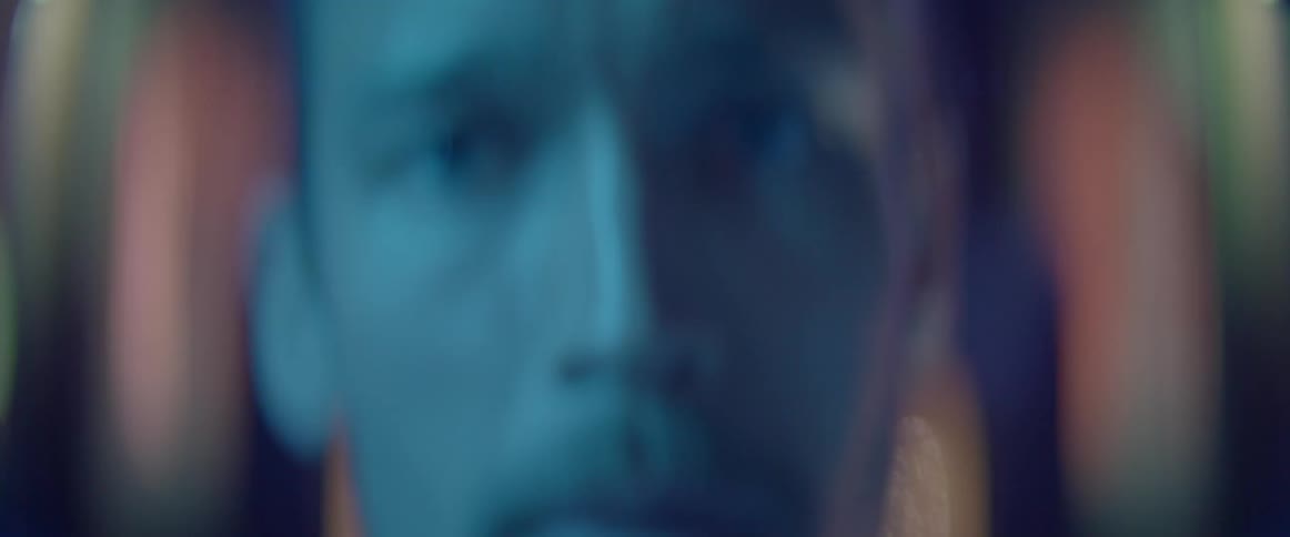 A blurry face of a stressed man talking angrily under blue neon lighting.