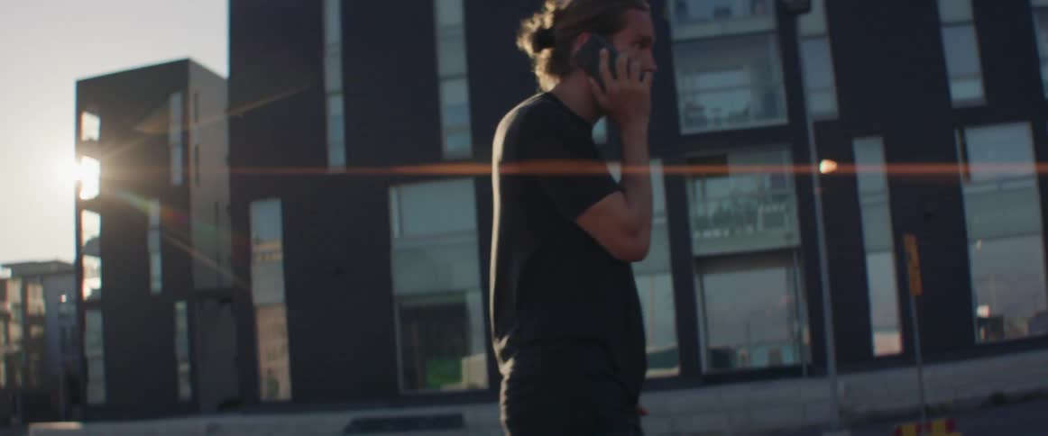 A man walks outside while dialing on his phone