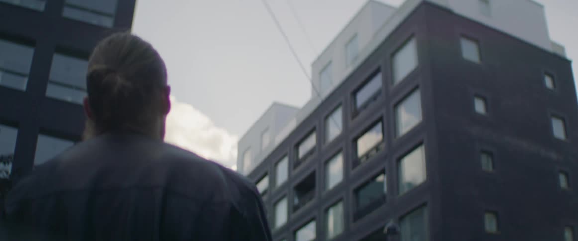 A man stands in the street looking up at the sky