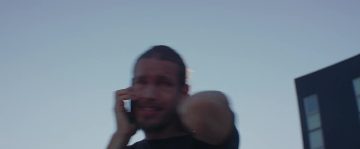 A distressed guy paces around anxiously while having a tense phone call outside.
