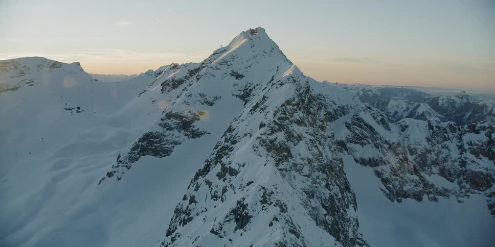 The sun sets behind snowy mountains