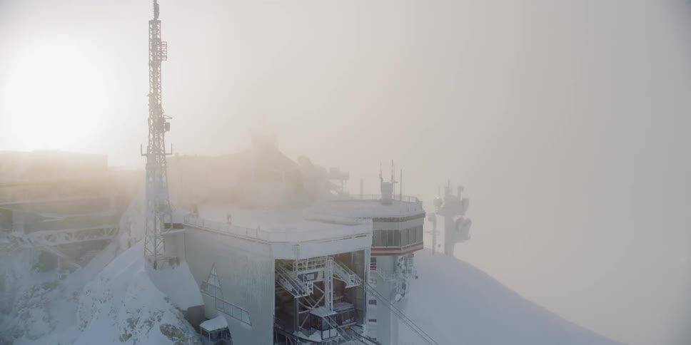 A building sits on a snowy mountain peak at sunset