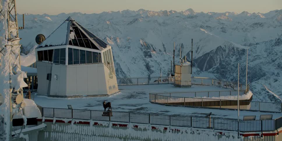 Resort building on top of snow covered mountain peak at sunset