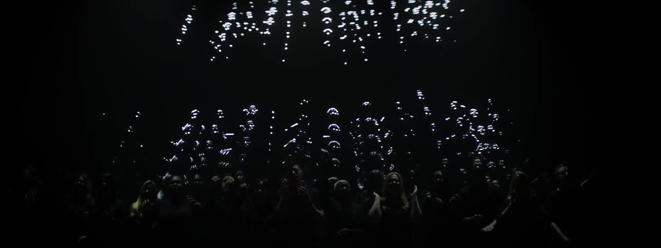 A choir sings while lights and images are projected on the wall behind them