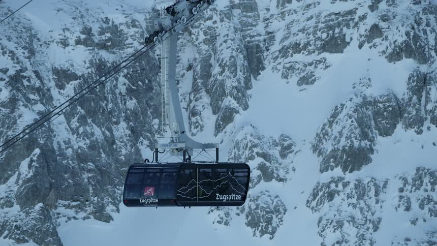 A gondola travels up a snowy mountainside