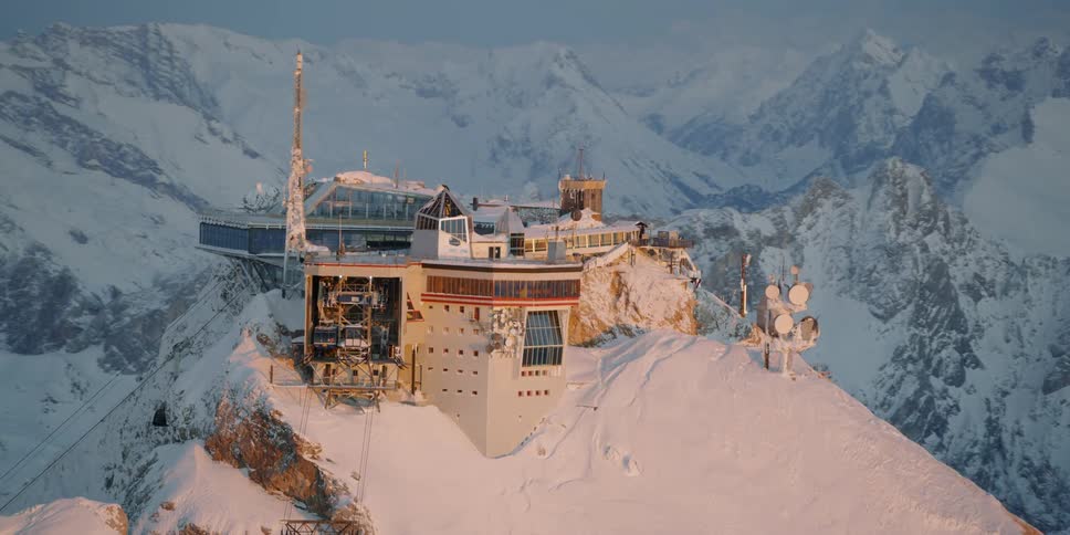 A large building sits atop a snowy mountain
