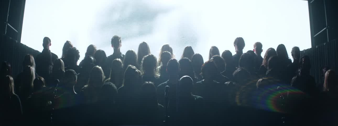A choir sings while images are projected behind them