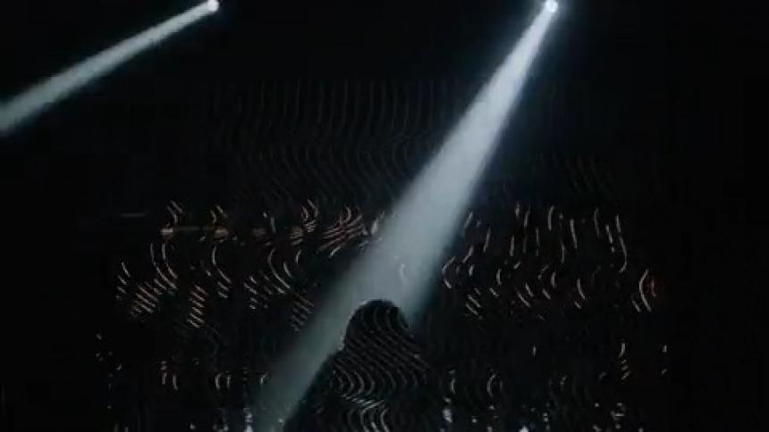 A person is performing in front of a crowd in the dark