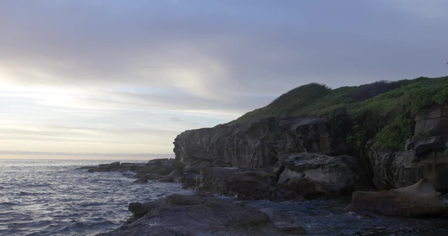 View of a rocky shore with a cliff on a cloudy day