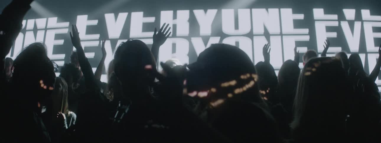A choir sings while lights flash and words are projected behind them