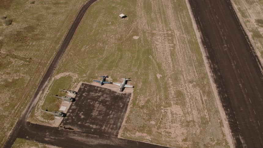 The runway has some aircrafts parked on the grass