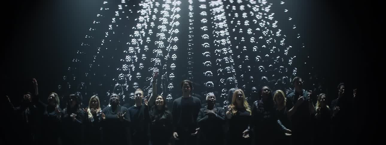 A choir sings while their images are projected behind them