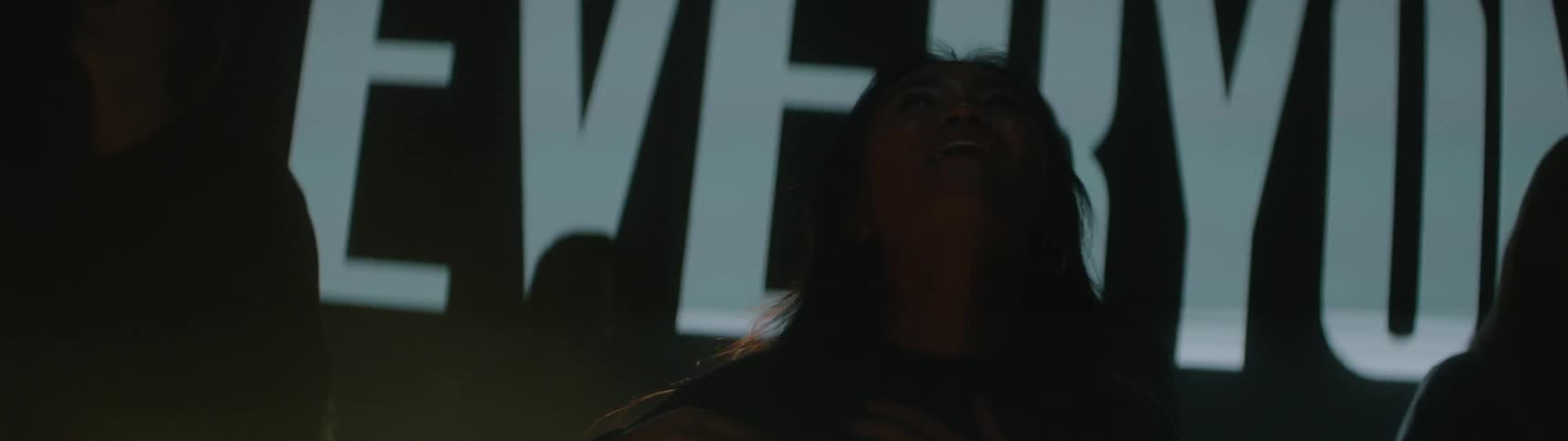 A group of young teens walk joyfully through a dim club