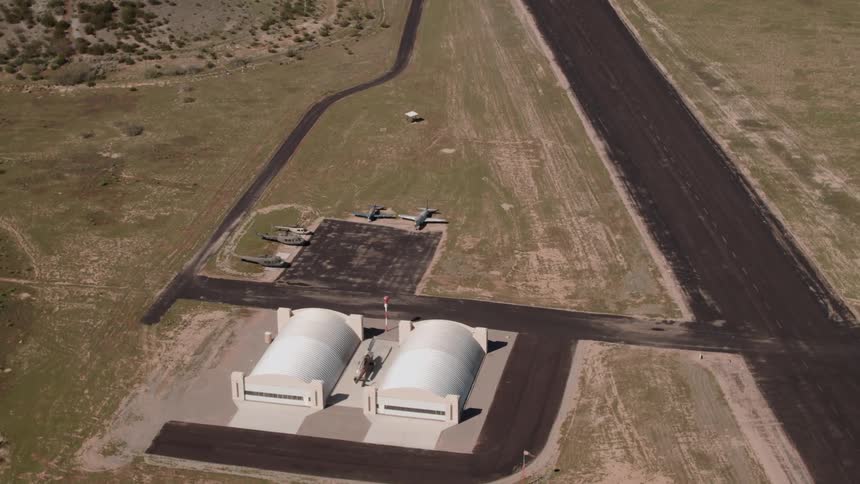 Two hangars side by side next to a roadway for flying vehicles