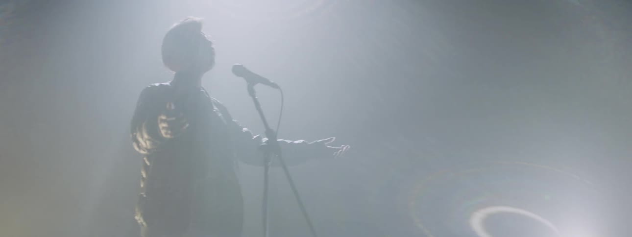 A woman is performing on stage singing in the dark