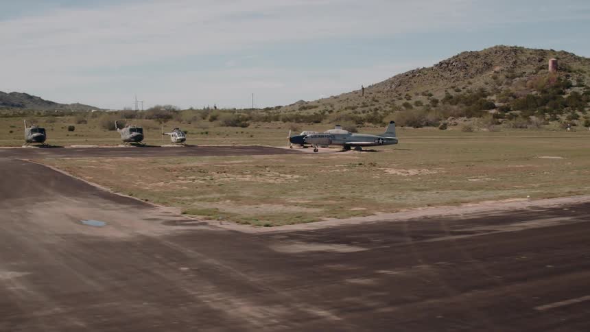 Airplanes and helicopters are parked at a rural airport