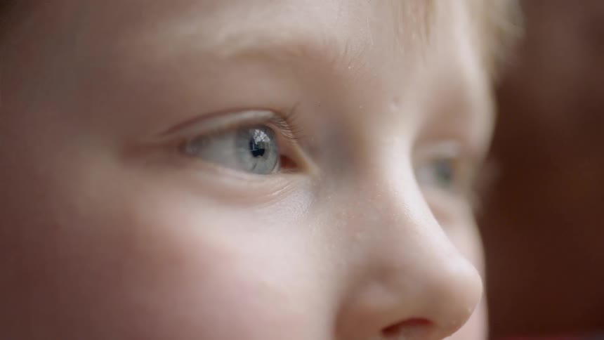 A boy is blinking his eyes in daylight