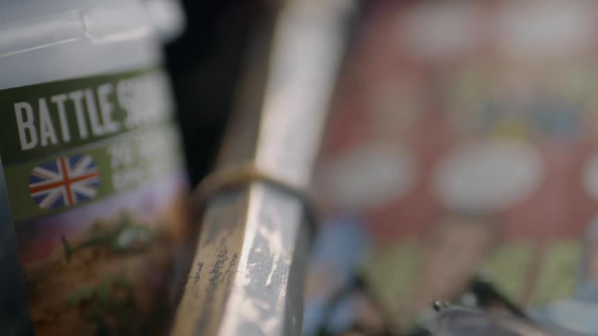 A model sword in a holder near comic books and toys