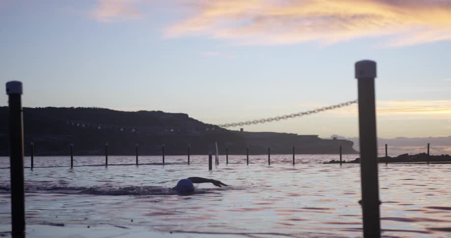 Man swimming in some water as the sun sets