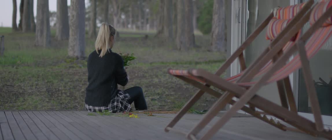 Woman sits down on a porch arranging a bouquet