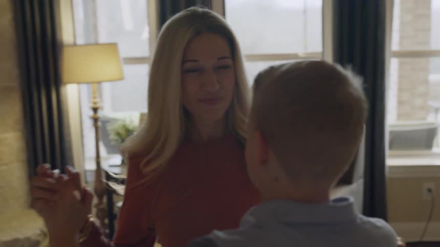 A woman is dancing with her son in the living room