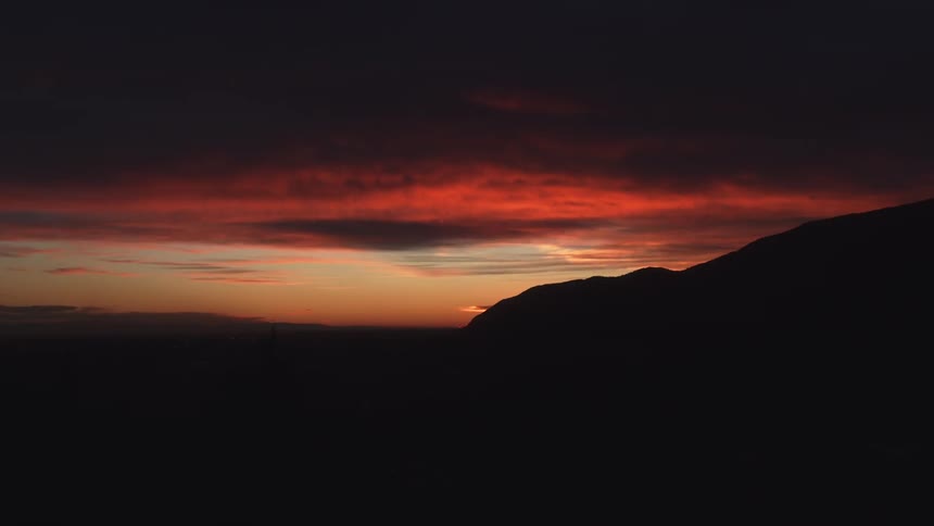 Sunset over the hills causes clouds and sky to color