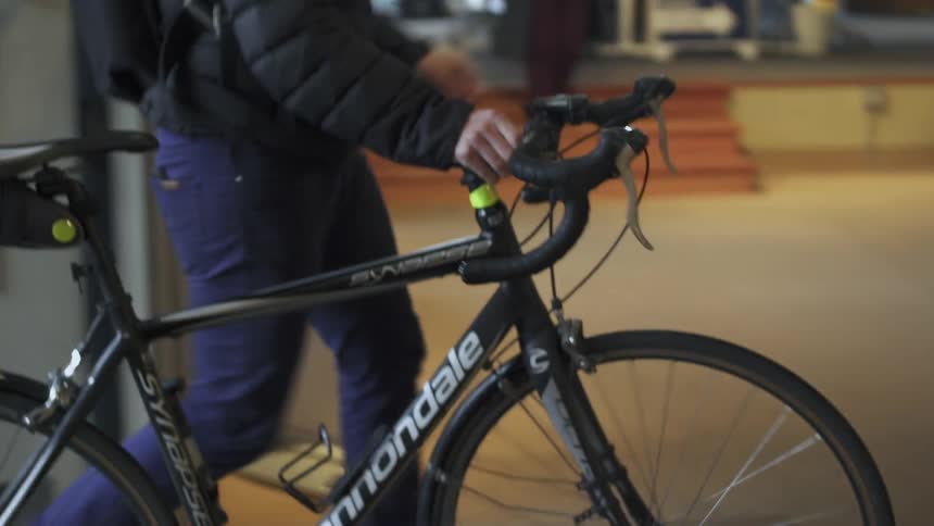 A man enters a building while pushing a bicycle