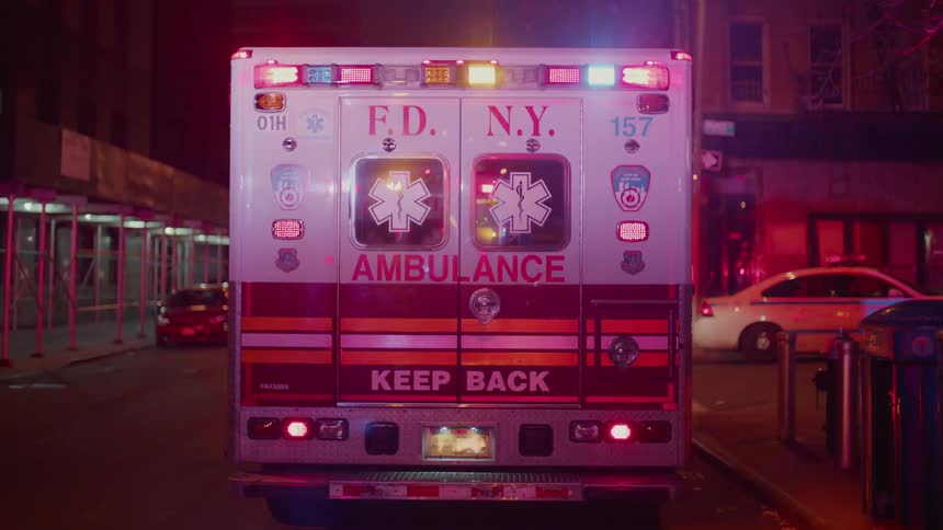 Ambulance parked outside at night in city with lights flashing