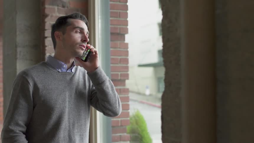 A man is talking on his phone by the window
