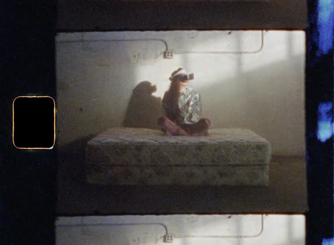 A woman wears a virtual reality headset while sitting on a mattress