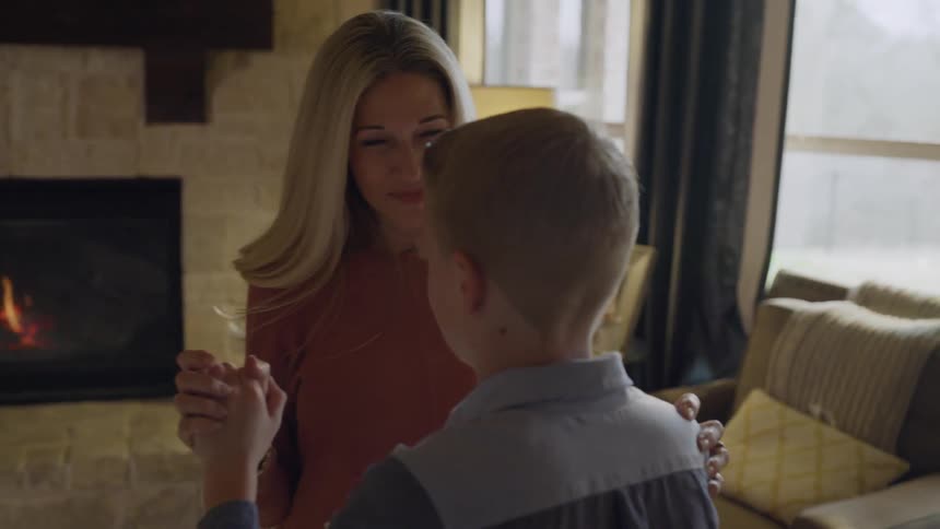 A mother dances with her son in the living room