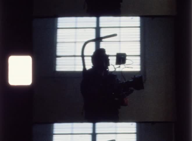 Person walking in a dim room carrying camera equipment