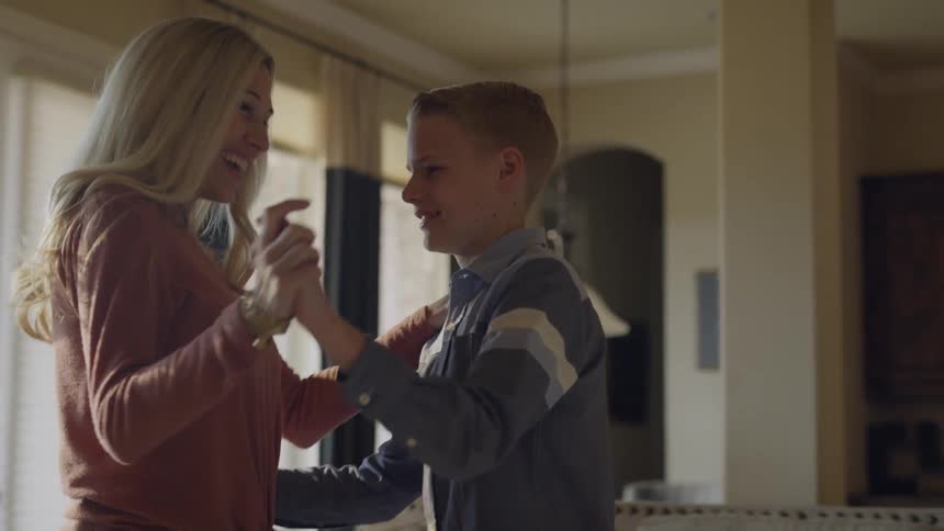 A woman smiles as she dances with a boy