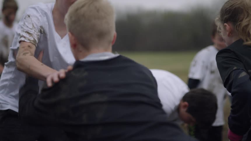 Kids play football in a muddy field
