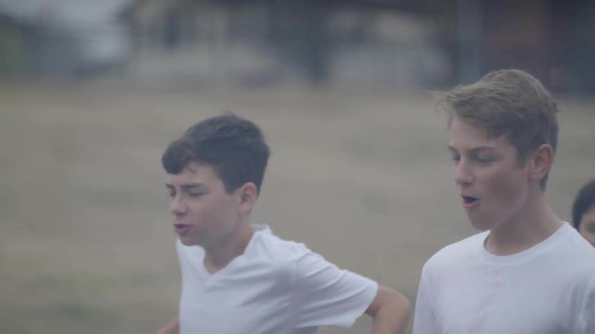 A group of boys are shouting as they walk on a field during a football game